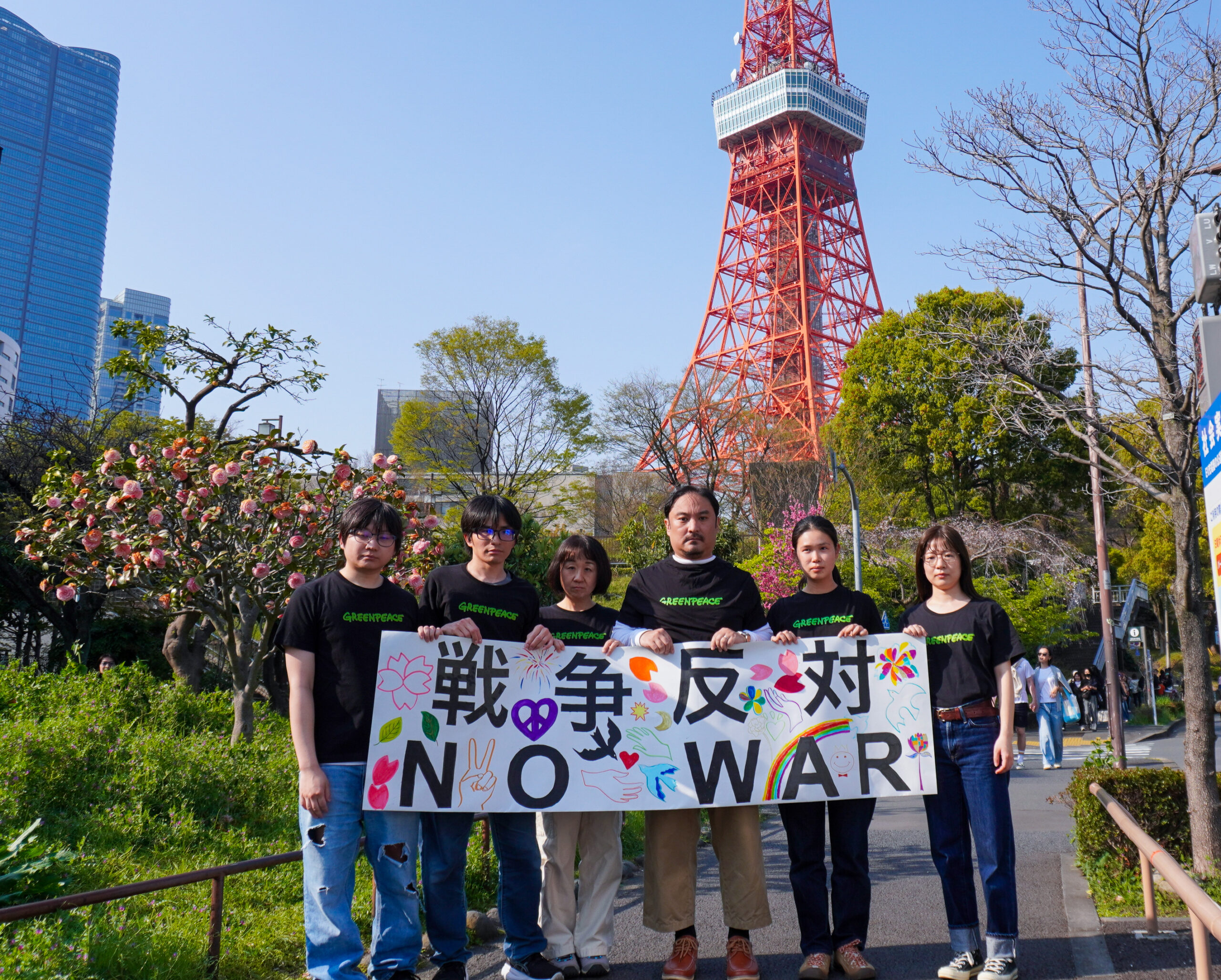 東京タワーの前で「戦争反対」のバナーを掲げるグリーンピース・ジャパンのボランティア