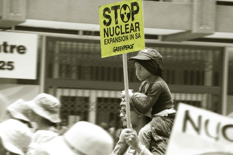 image of young boy atop the shoulders of his father, while he walks in a march against climate change.