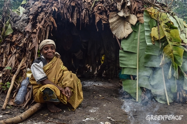 Indigenous Woman sitting next to a hut. 