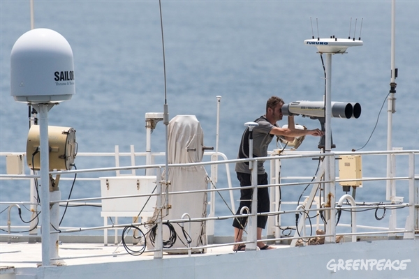 Greenpeace campaigner Pavel Klinckhamers looks out for fishing boats with binoculars from the Esperanza's monkey island. Greenpeace is on tour in West African waters to address the problem of overfishing in the region.