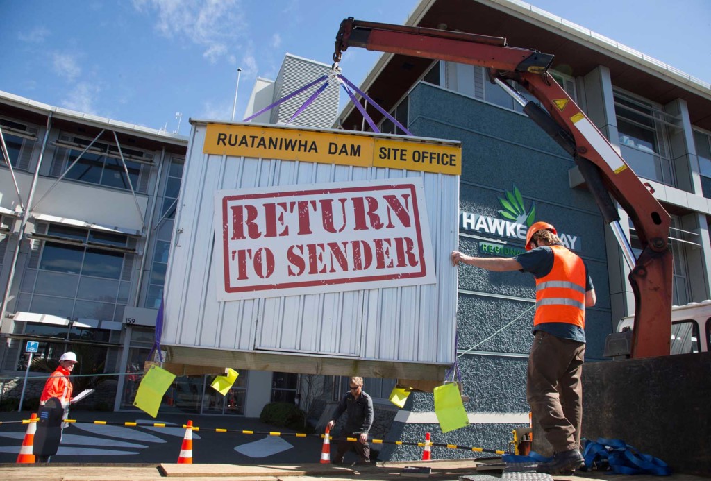 Greenpeace activists wearing high vis use a crane to unload the Ruataniwha Dam site office - a shipping container which has a sign attached reading 'return to sender' - at the Hawke's Bay Regional Council building.