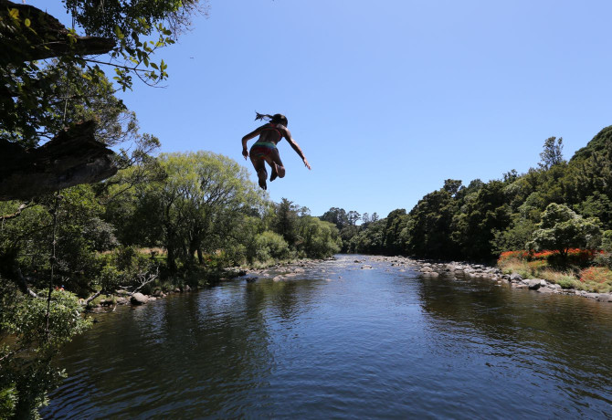A wide angle shot of a swimmer jumping into a river A wide angle shot of a person jumping into a river