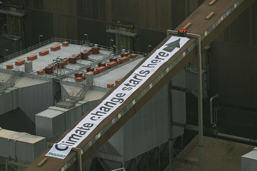 Four members of the Greenpeace climate rescue team scale the 150-metre high smoke stack at the Huntly coal-fired power station and start unfurling a banner that reads: "Climate killer". In 2007, Greenpeace activists climbed the Huntly power station and deployed banners in protest against the plant's use of coal in the climate crisis. © Greenpeace / Dean Treml