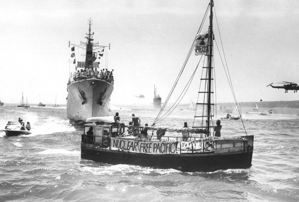 The USS Pintado submarine, escorted by the HMNZS Waikato (the same frigate sent to Moruroa test zone in 1973 by the New Zealand Government), is met by the Peace Squadron as it arrives in Waitemata harbour, Auckland in 1978. The vessel in the foreground is the Alliance - a scow which was part of the Peace Squadron. The growing anti-nuclear movement in New Zealand was hostile to visits from US ships because the Americans refused to confirm or deny whether their ships carried nuclear weapons. Public opinion was increasingly in favour of banning these visits. Between 1978 and 1983 opposition to nuclear-armed ship visits rose from 32% to 72%. In 1985 the Government effectively banned nuclear ship visits. New Zealand was the first country to declare itself nuclear free when it passed legislation in 1987.