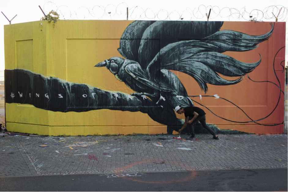 Artist Sokar Uno giving the final touches to his bird of paradise mural in Tempelhof, Berlin.