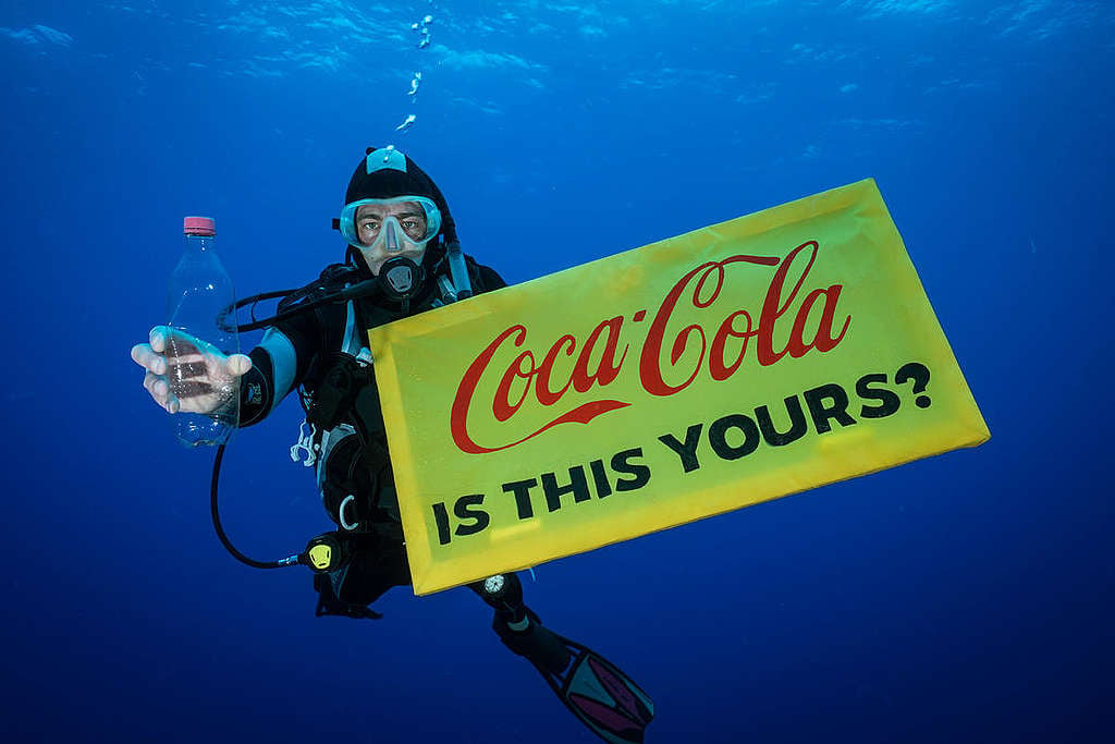 A Greenpeace diver holds a banner reading "Coca-Cola is this yours?" and a Coca-Cola bottle found adrift in the garbage patch.  The crew of the Greenpeace ship MY Arctic Sunrise voyage into the Great Pacific Garbage Patch document plastics and other marine debris. The Great Pacific Garbage Patch is a soupy mix of plastics and microplastics, now twice the size of Texas, in the middle of the North Pacific Ocean.