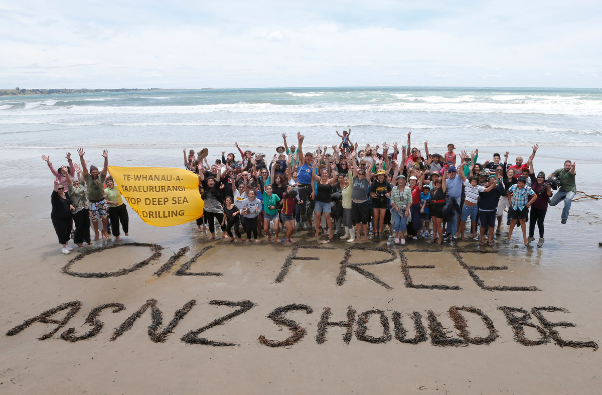 Greenpeace crew and members of Te Whanau a Apanui (Maori group) celebrate the withdrawal of oil giant Petrobras which had planned to drill for deep sea oil off Whangaparaoa, East Cape. A message made from seaweed reads 'Oil free as NZ should be'.