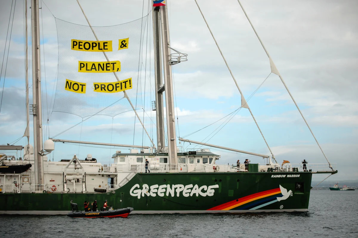 Photo of Rainbow Warrior flying a People>Profit banner