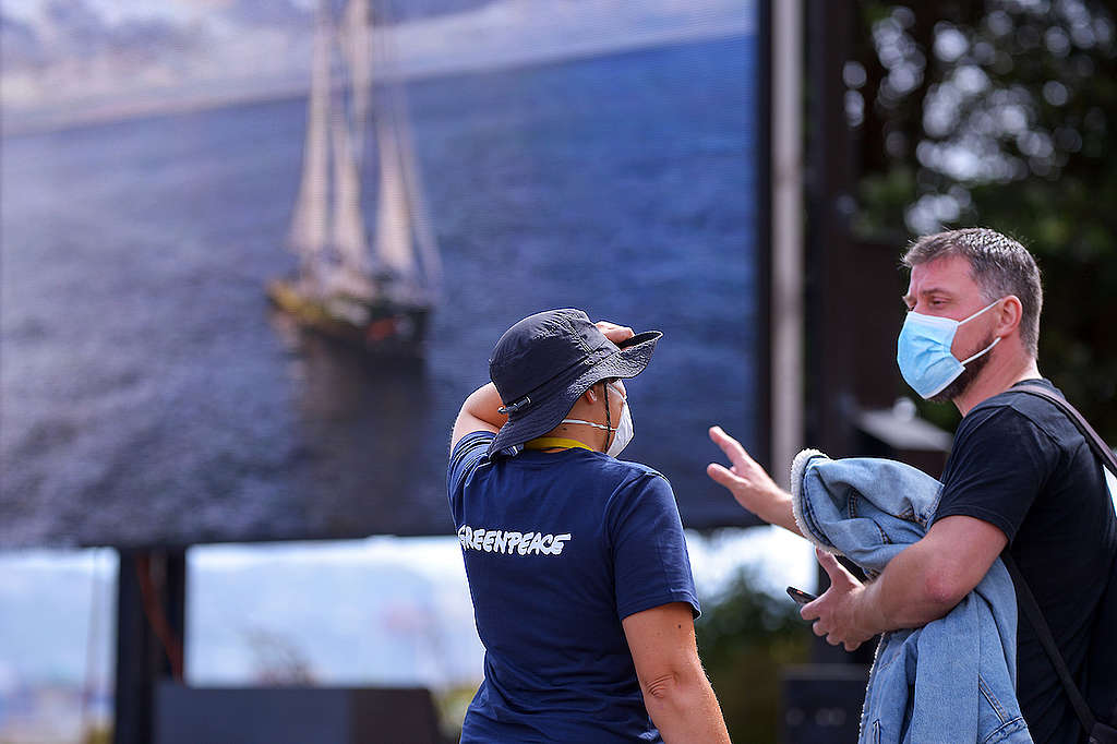 A Greenpeace campaigner talks to a member of the public in front of the digital video billboard in Wellington.