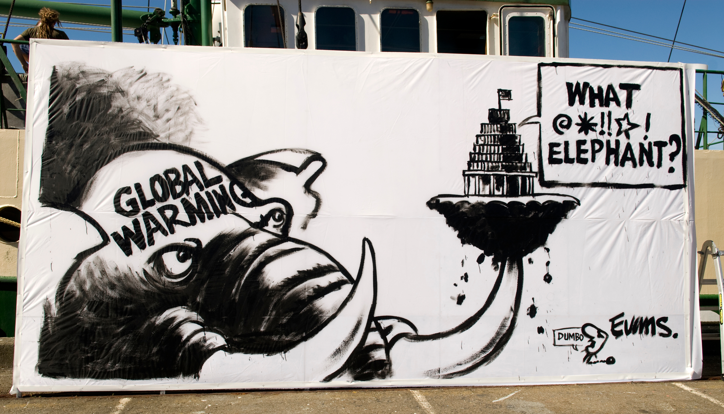 A giant cartoon painted on a billboard shows an elephant named global warming holding the beehive on one tusk and speech from inside the beehive says: What BLEEP elephant??