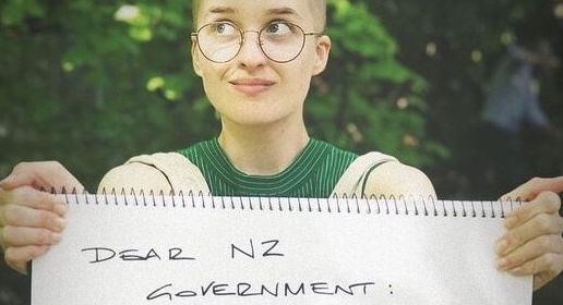 A person in green with a hand written TakeawayThrowaways sign