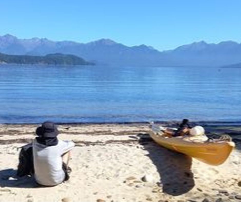 person and kayak on the shoreline of a flat lake