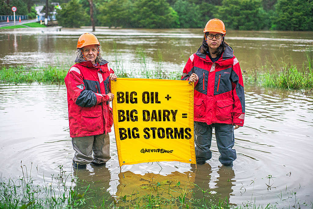 Climate campaigner Christine Rose and another Greenpeace activist hold a banner in flooding of Christine's local community caused by Cyclone Gabrielle