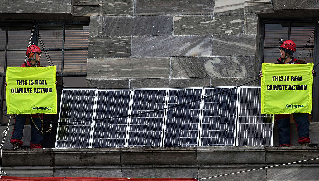 Four Greenpeace activists climb on the roof of Parliament Building in Wellington and install half a dozen solar panels. They have also unfurled a large banner with a satirical message about Prime Minister John Key. While on the roof, the activists are using the solar panels to power a wifi hub and communicate to people from around New Zealand. The aim of the protest is to expose the Key Government's failure to act on climate change, which has seen pollution increase and New Zealand miss out on creating thousands of clean energy jobs. Greenpeace is asking the government to put in place a real climate action plan, which would shift the country towards running on 100% clean energy."