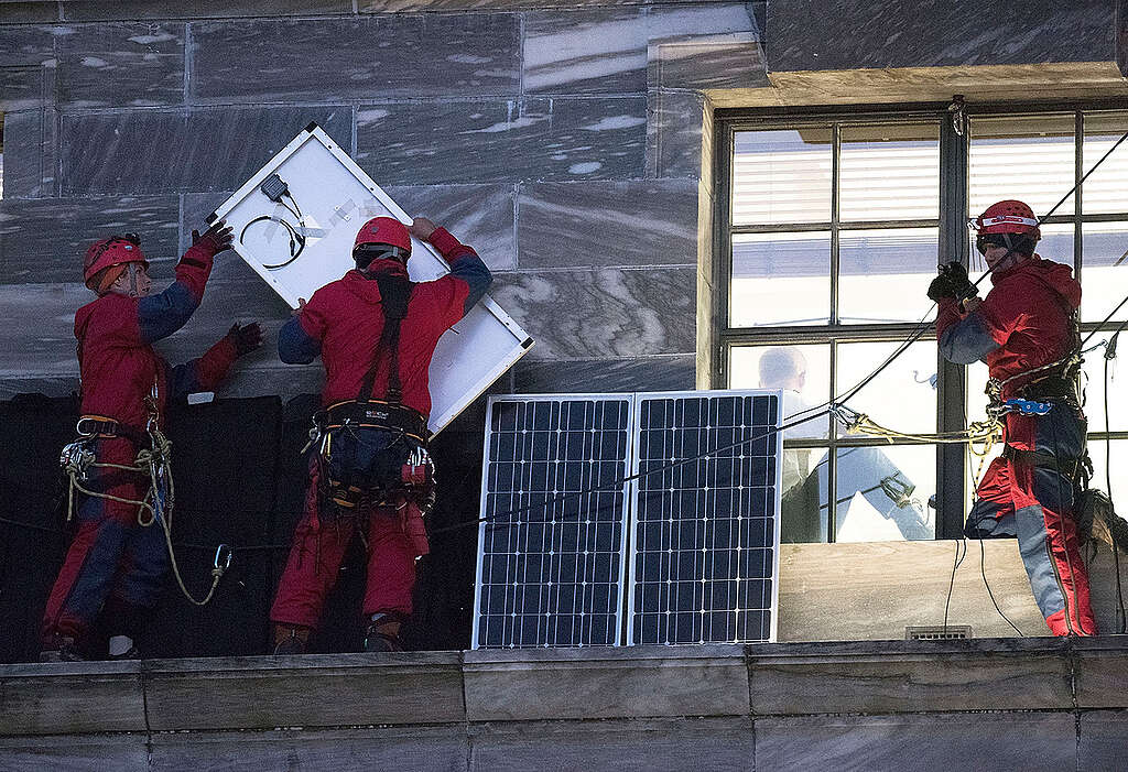 Four Greenpeace activists climb on the roof of Parliament Building in Wellington to install half a dozen solar panels.