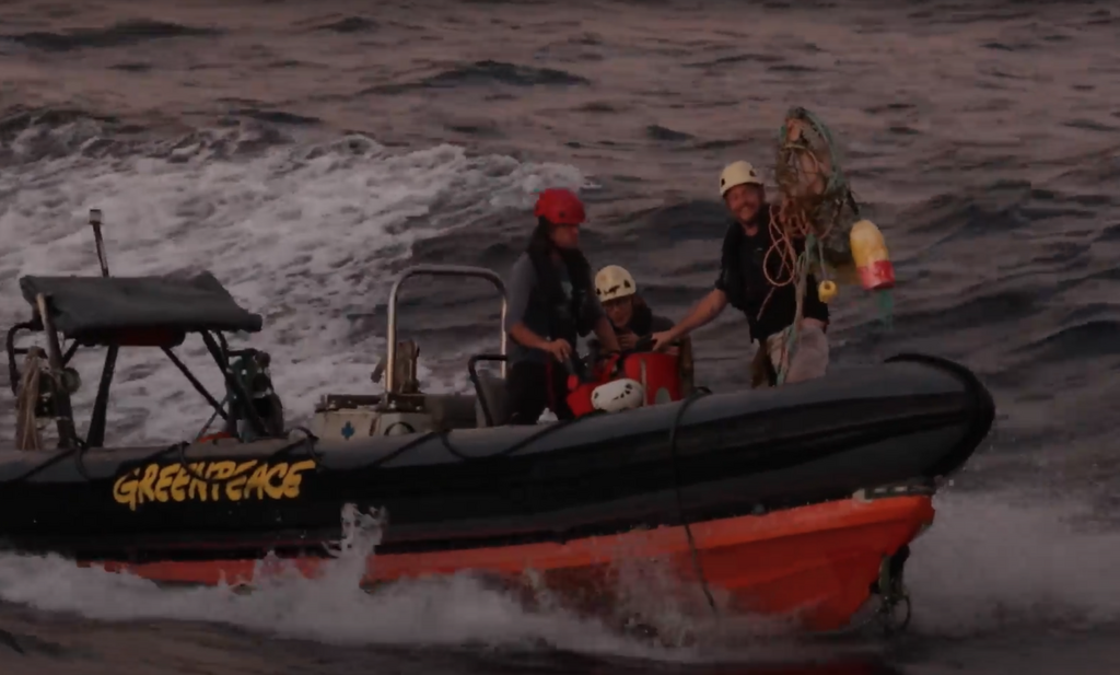 Ignacio Soaje, Chief Mate on Arctic Sunrise in a Greenpeace inflatable boat holds the fishing gear they removed from the stricken whale