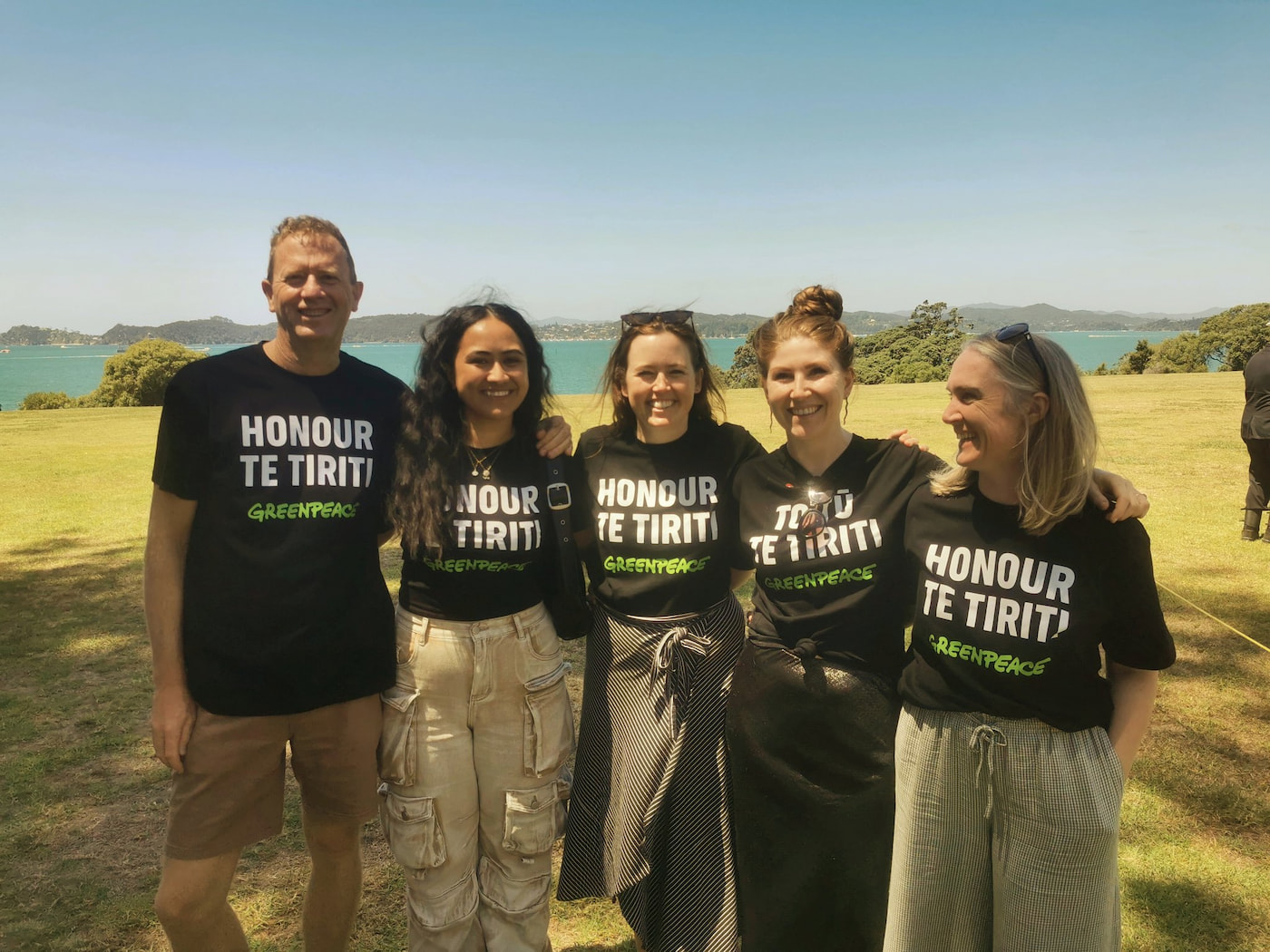 Russel Norman, Fili Fepulea’i, Jess Desmond, Niamh O’Flynn and Emma Page of Greenpeace Aotearoa at Waitangi wearing Honour TeTiriti / Toitū Te Tiriti shirts in 2024