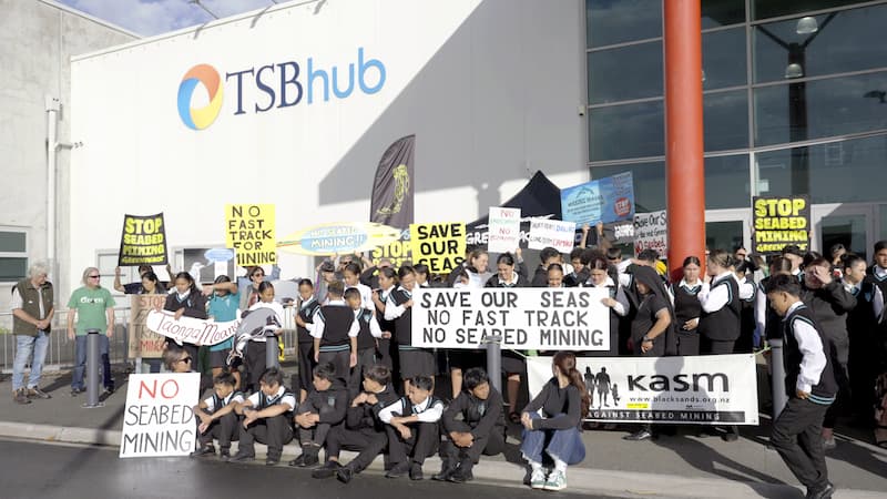 Opposition to seabed mining gathers outside the EPA hearing where Trans Tasman Resources Ltd is once again making a bid for content to start seabed mining in the Taranaki Bight where they propose to suck up 50 million tonnes of sand every year for 30 years, dumping most back in giant sediment plumes after extracting the vanadium.