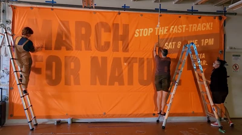 Greenpeace staff paint a March For Nature banner in the Greenpeace warehouse