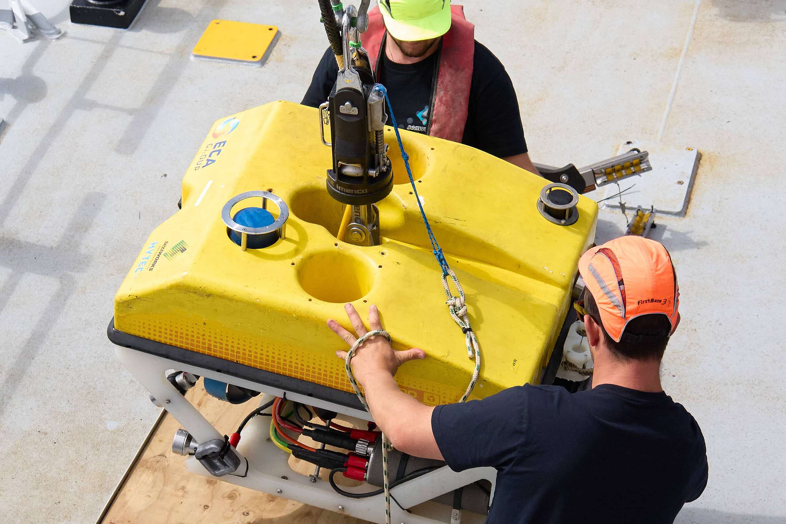 Two people on board the ship used for the Greenpeace Seamount Expedition work with the yellow remote operated vehicle