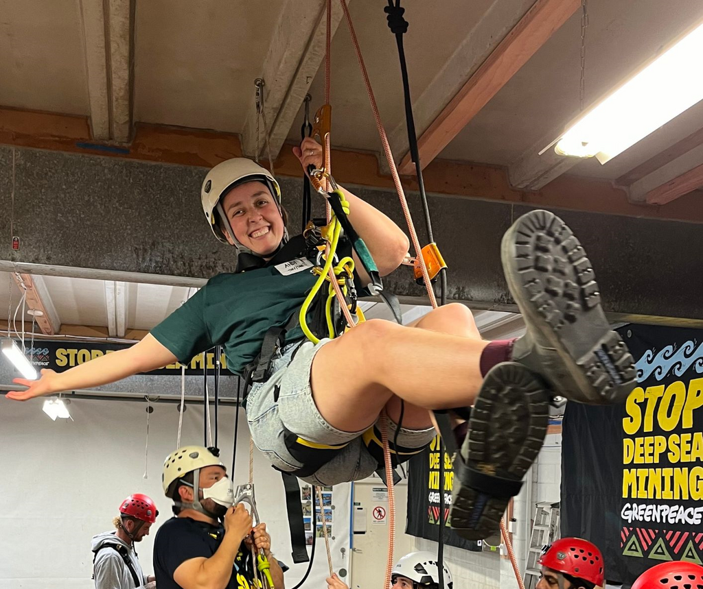 A volunteer in a climbing harness swings from a rope attached to the ceiling during Basic Actions Training