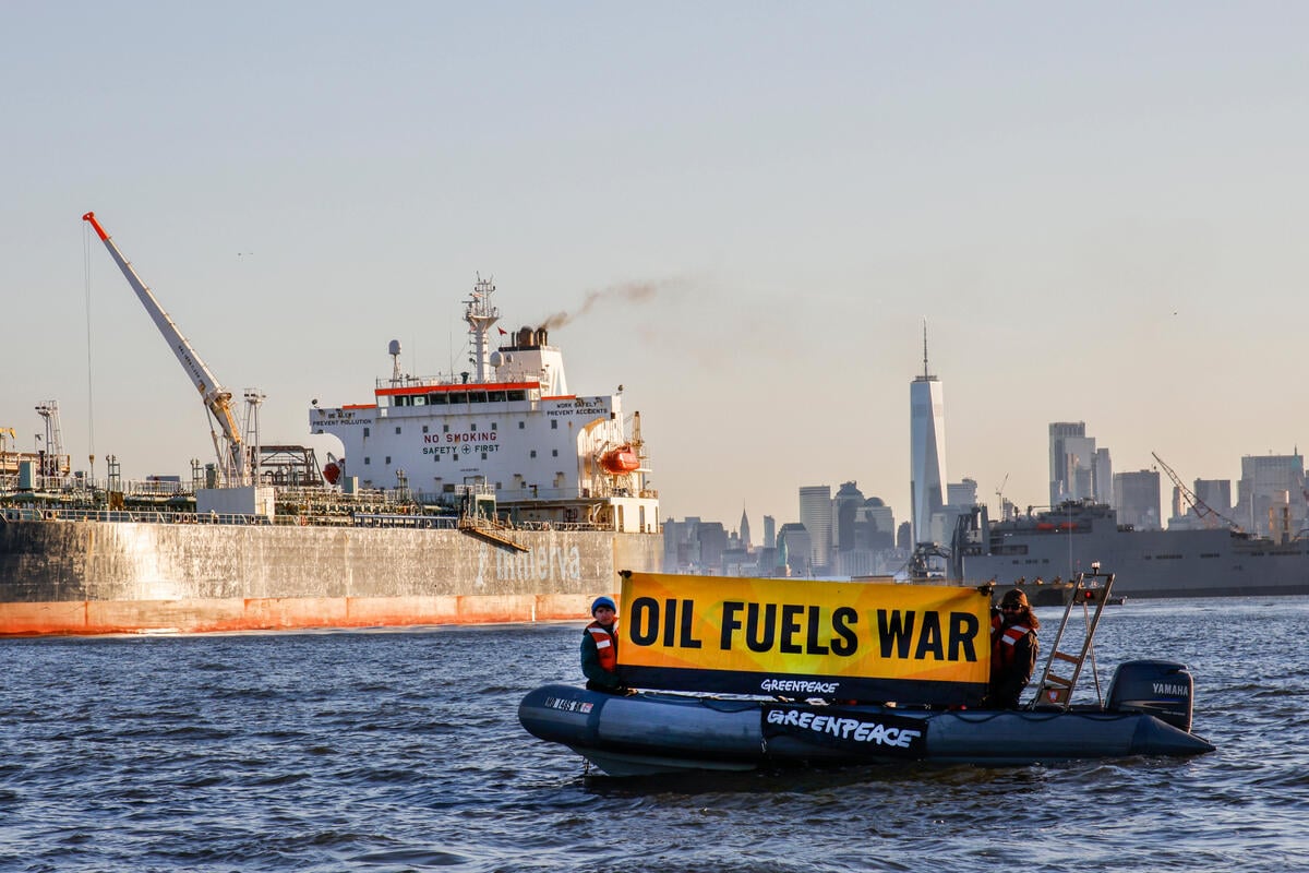 Oil fuels war banner on a Greenpeace inflatable boat
