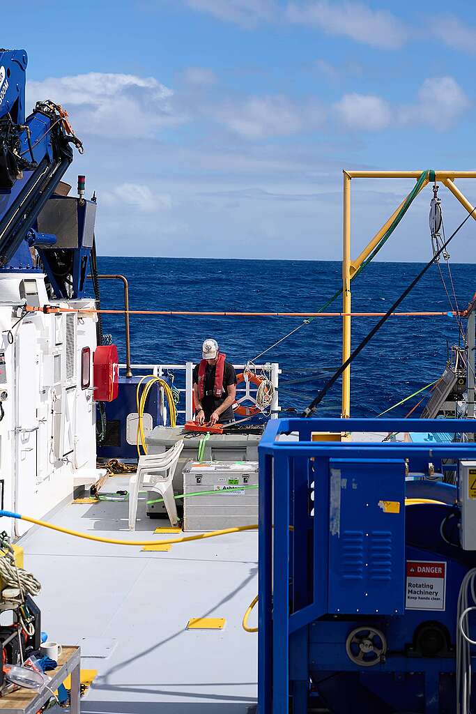 John Murphy, technician on the Greenpeace Seamount Expedition works on tech with a calm sea behind him