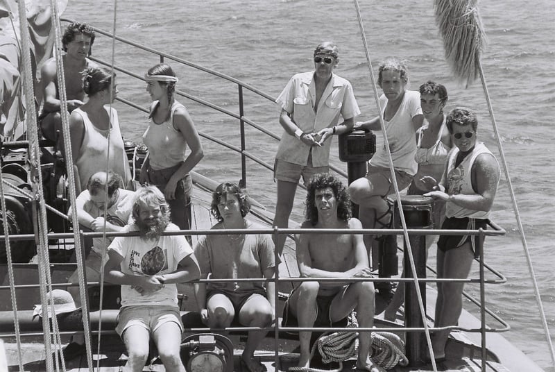 A black and white group shot of crew members relaxing on a boat