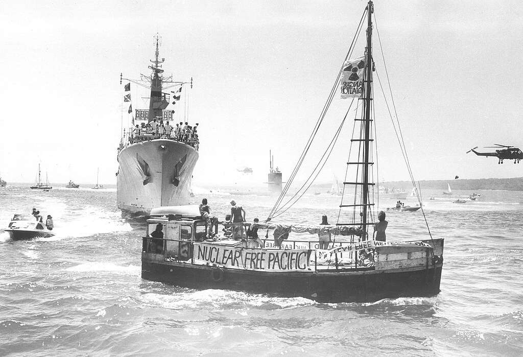 The USS Pintado submarine, escorted by the HMNZS Waikato (the same frigate sent to Moruroa test zone in 1973 by the New Zealand Government), is met by the Peace Squadron as it arrives in Waitemata harbour, Auckland in 1978. The vessel in the foreground is the Alliance - a scow which was part of the Peace Squadron. The growing anti-nuclear movement in New Zealand was hostile to visits from US ships because the Americans refused to confirm or deny whether their ships carried nuclear weapons. Public opinion was increasingly in favour of banning these visits. Between 1978 and 1983 opposition to nuclear-armed ship visits rose from 32% to 72%. In 1985 the Government effectively banned nuclear ship visits. New Zealand was the first country to declare itself nuclear free when it passed legislation in 1987. The USS Pintado submarine, escorted by the HMNZS Waikato (the same frigate sent to Moruroa test zone in 1973 by the New Zealand Government), is met by the Peace Squadron as it arrives in Waitemata harbour, Auckland in 1978. The vessel in the foreground is the Alliance - a scow which was part of the Peace Squadron. The growing anti-nuclear movement in New Zealand was hostile to visits from US ships because the Americans refused to confirm or deny whether their ships carried nuclear weapons. Public opinion was increasingly in favour of banning these visits. Between 1978 and 1983 opposition to nuclear-armed ship visits rose from 32% to 72%. In 1985 the Government effectively banned nuclear ship visits. New Zealand was the first country to declare itself nuclear free when it passed legislation in 1987.