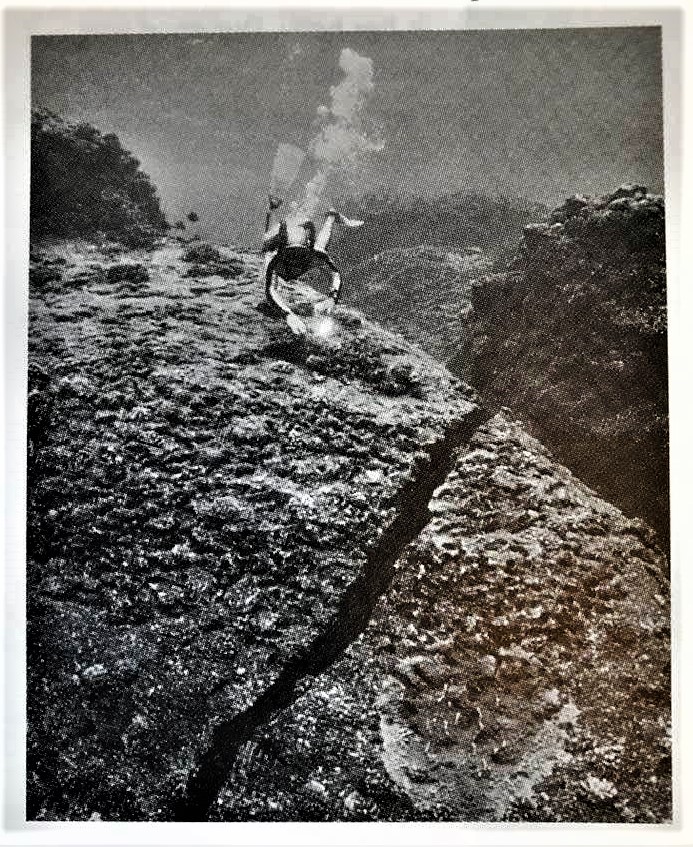 Cousteau expedition diver examines a fissure in the coral at Moruroa Atoll, 1987.