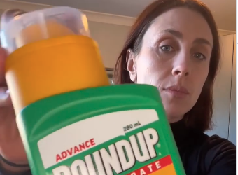 Gen looking concerned holding a container of Roundup close to the camera Gen looking concerned holding a container of Roundup close to the camera