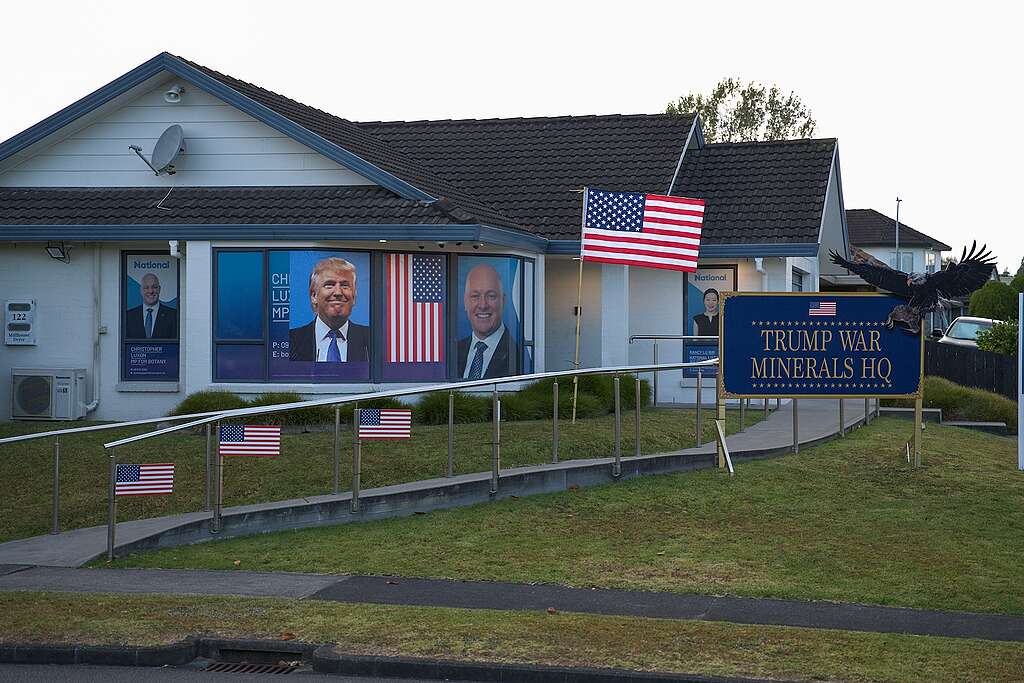 A house with Trump's face and PM Christopher Luxon's face on windows; US flags on lawn; a sign saying TRUMP WAR MINERALS HQ