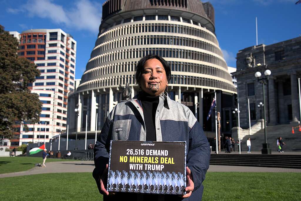 Campaigner Juressa Lee in front of Parliament with a box saying 26,516 demand no minerals deal with Trump