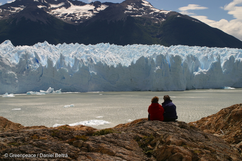 Dos activistas de Greenpeace mirando hacia el borde del Glaciar Upsala en el Parque Nacional Los Glaciares. Al fondo se ven las montañas. El Arctic Sunrise recorrerá la Patagonia y Chile durante 4 semanas, investigando hasta qué punto están desapareciendo los glaciares y los campos de hielo. Los hallazgos del equipo de investigación confirman que varios grandes glaciares, como los glaciares San Quintín y Upsala, que forman parte de los campos de hielo de la Patagonia Norte y Sur, se han adelgazado significativamente y han retrocedido varios kilómetros en los últimos años.