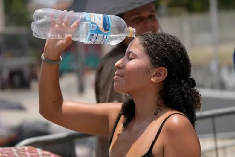 Mujer se refresca el rostro utilizando una botella con agua