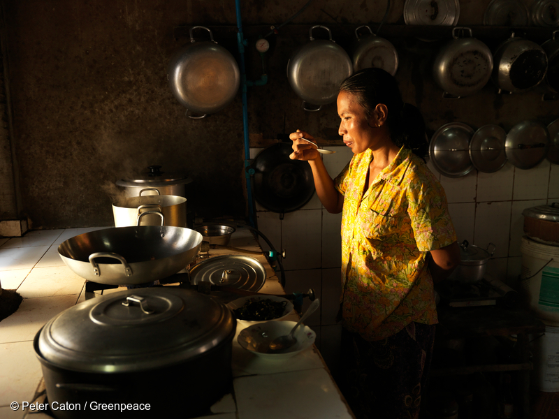 Mujer cocinando rodeada de ollas y sartenes.