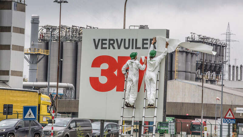 Activisten van Greenpeace België hangen een spandoek op met de tekst 'De vervuiler betaalt' aan het hoofdkantoor van 3M, verantwoordelijk voor PFAS-vervuiling in Antwerpen.