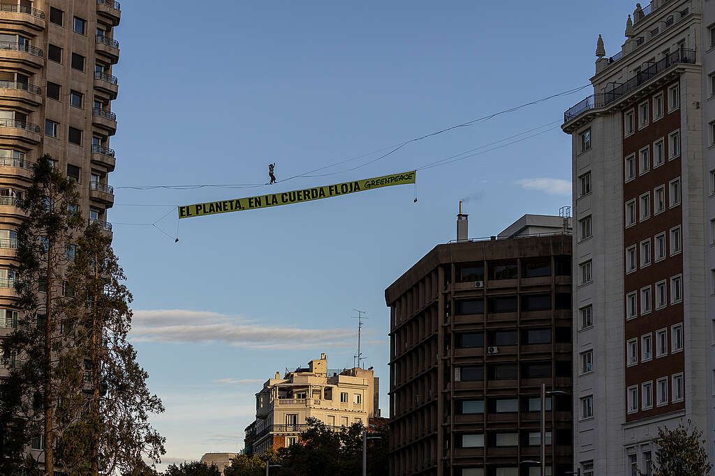 Un militant de Greenpeace marche sur une corde raide à 30 mètres au-dessus du centre de Madrid avec une banderole de 30 mètres carrés portant le slogan « La planète sur la corde raide ».