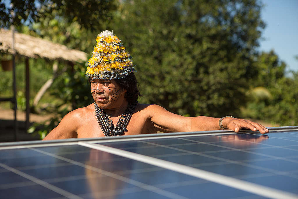 Cacique Munduruku ao lado de placa de energia solar.
