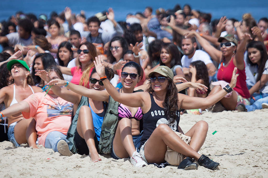 Pessoas sentadas na montagem do banner humano em defesa dos Corais da Amazônia.