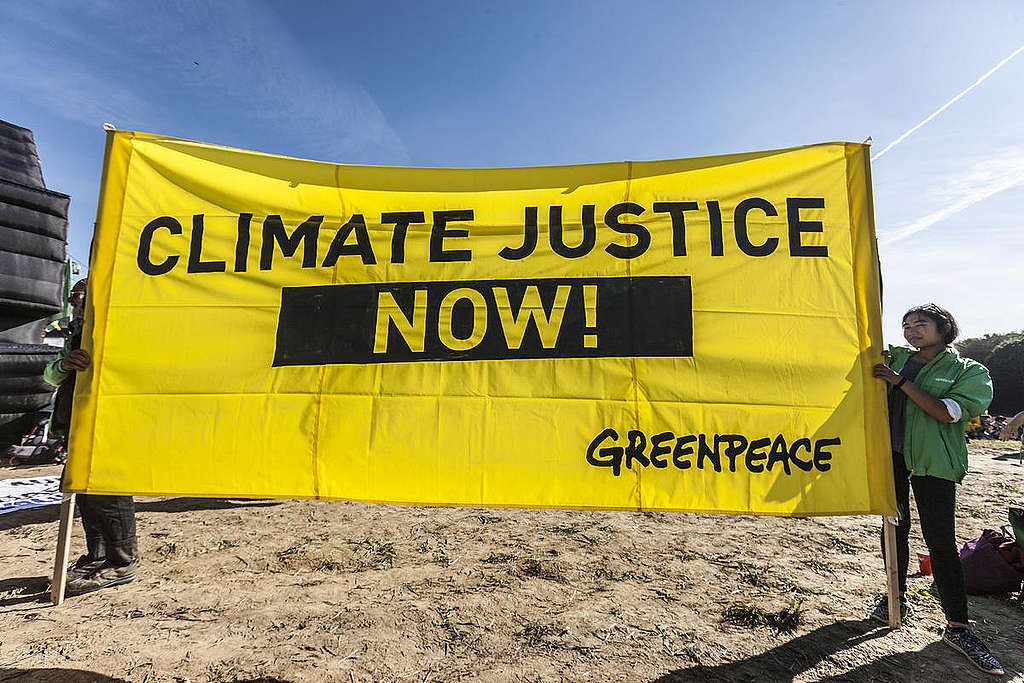 Manifestantes seguram placa que diz: "Justiça para o clima agora!"