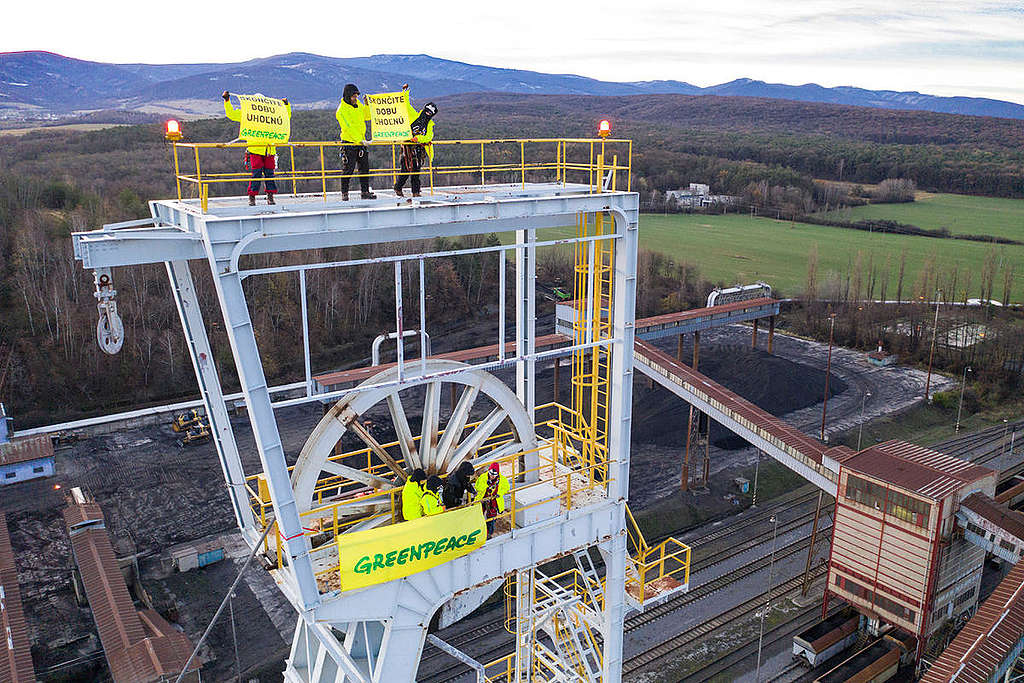 Ativistas do Greenpeace seguram um banner em uma torre de uma mineradora