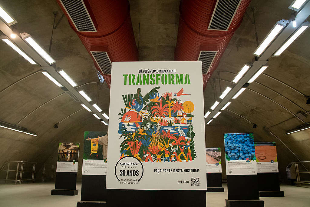 Foto em primeiro plano mostrando seis banners situados a diferentes distâncias numa plataforma do metrô. Cada banner possui uma foto diferente de um momento histórico do Greenpeace.
