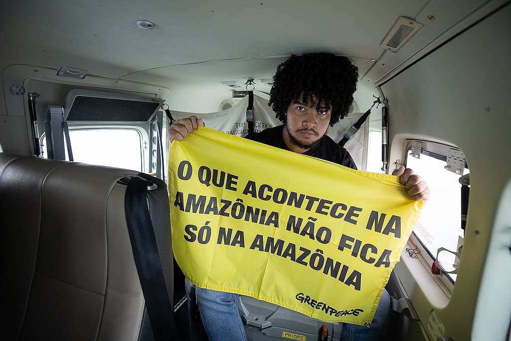 Voluntário do Greenpeace Brasil, Rui Gemaque Jr, que acompanhou o sobrevoo segura o banner escrito ''o que acontece na Amazônia, não fica na Amazônia'' 