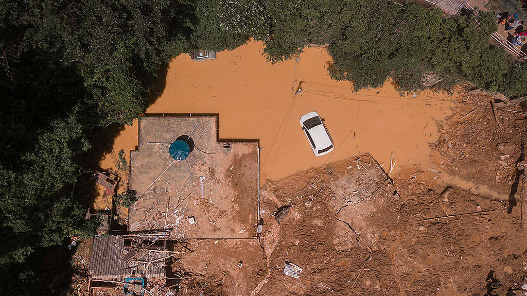 Casa atingida por enchente e carro inundado por água e lama 