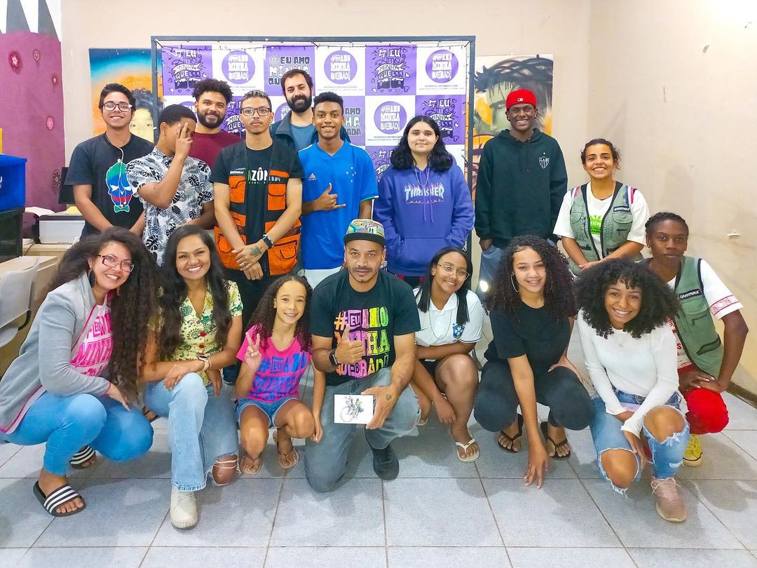Foto de pessoas voluntárias em frente ao painel do movimento Eu Amo Minha Quebrada.