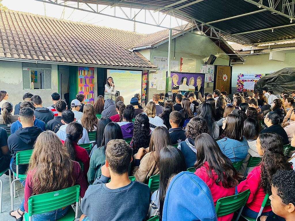 Foto de voluntária no ambiente externo da escola.