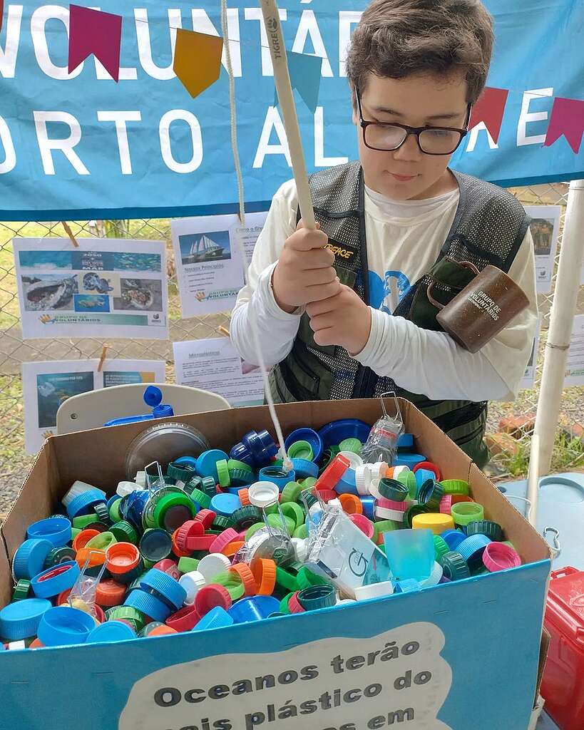 Foto de criança voluntária em brincadeira de pescaria com tampas de garrafa pet