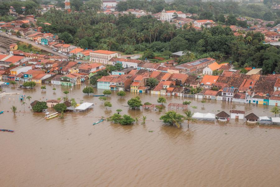 Foto de cima de cidade em Alagoas com ruas alagadas e casas cobertas parcialmente de água. 