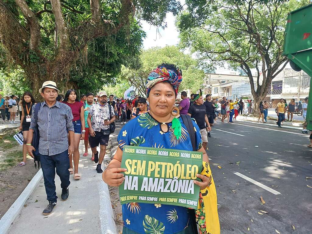 Mulher indígena com roupas coloridas segura uma placa com a frase "Sem petróleo na Amazônia"